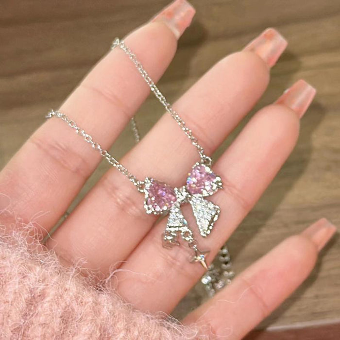 Pink bow pendant necklace with two bow charms and hanging star on silver-tone chain