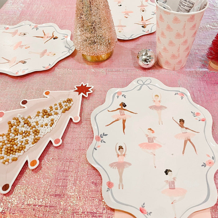 Christmas-themed paper plates on pink tablecloth: ballet dancers and pink tree designs