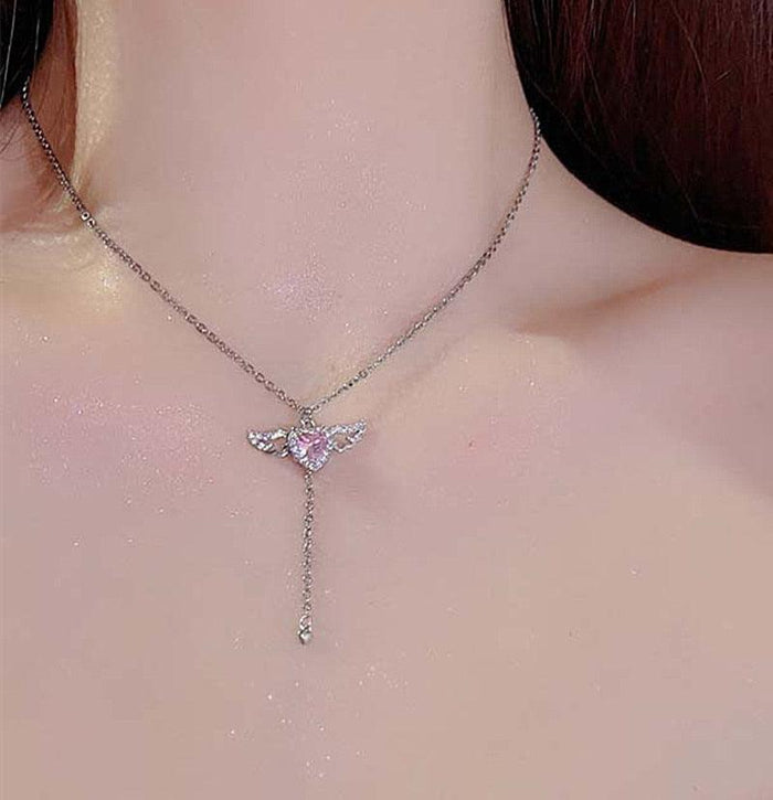 Silver-tone angel wings heart pendant necklace with pink crystal center on neckline