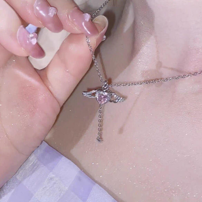Silver-tone heart angel wings pendant necklace held in hand with pink crystal heart center