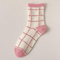 Crew socks with pink grid pattern and pink cuff on white fabric.
