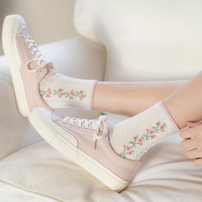 Floral crew socks with pink cuff border and small flower print on cream fabric.