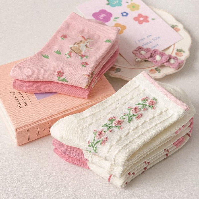 Assorted floral crew socks in pastel pink and cream, folded stack.