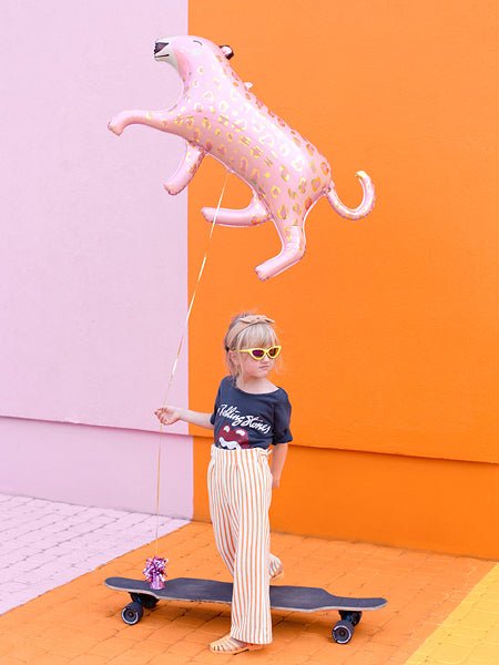 Pink leopard-print dog balloon floating above a child holding a leash-style string.