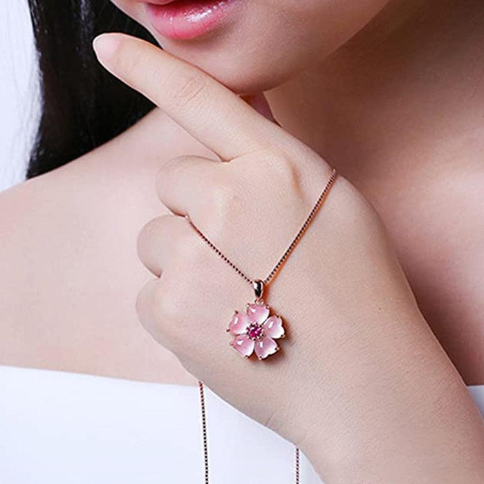Sakura pendant necklace on hand: thin chain with pink flower charm and magenta center