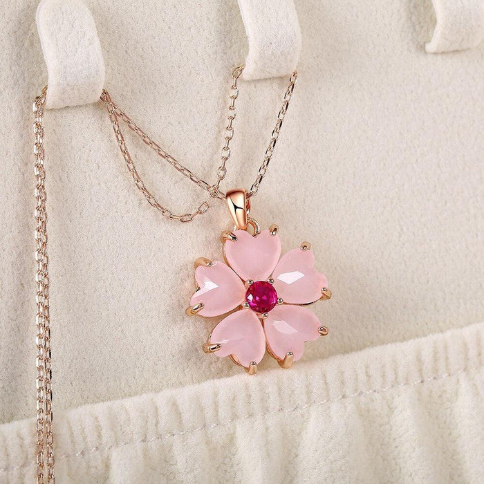Sakura pendant necklace displayed on stand: pink flower charm with magenta center and rose-gold chain