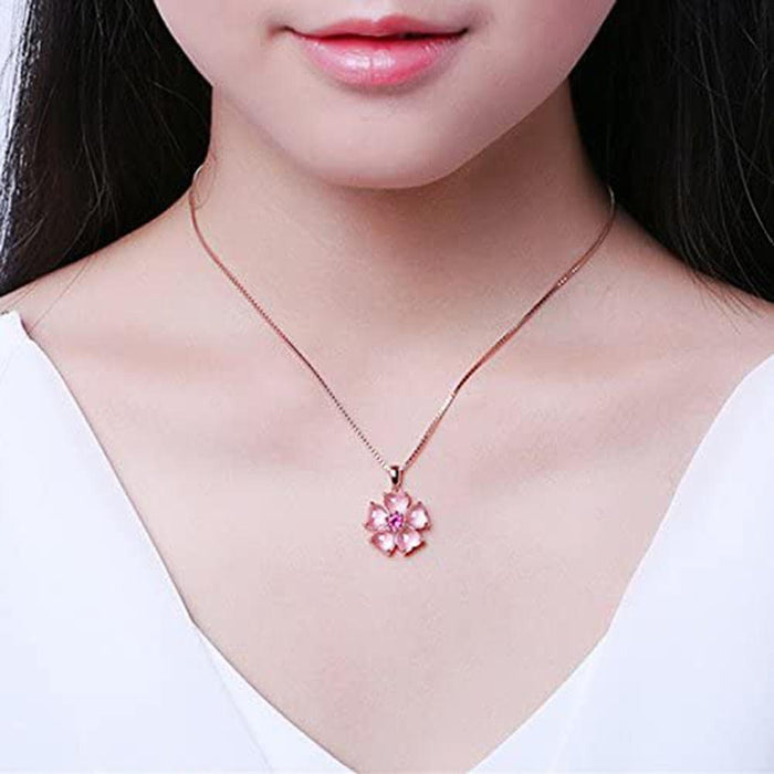 Sakura pendant necklace worn at neckline: pink flower pendant with magenta center and slim chain