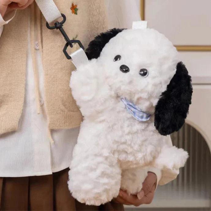 Plush crossbody bag shaped like white puppy with black ears, blue bandana, strap