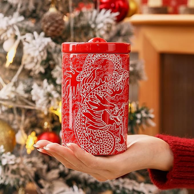 Red porcelain canister with white dragon pattern held in hands with round lid
