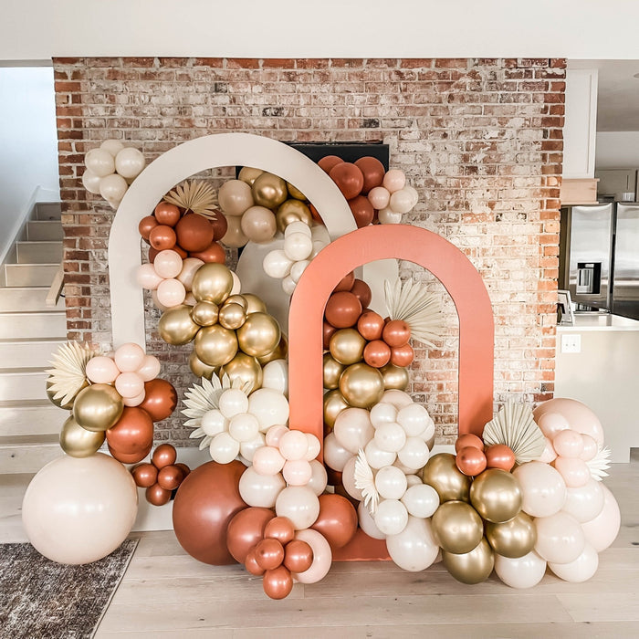 Balloon backdrop with blush, white, brown, and gold balloon clusters in arches