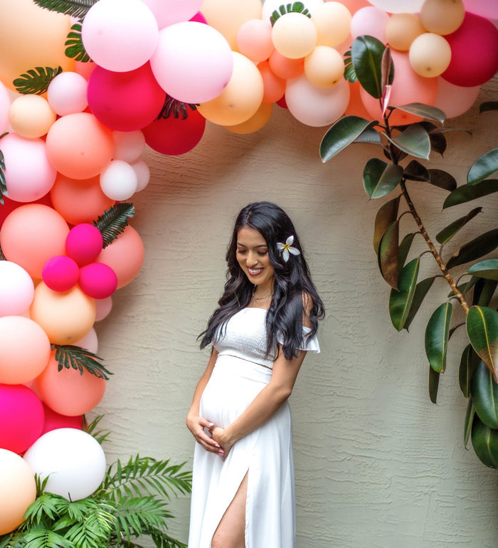 Coral and blush balloon arch with pink, white, and peach latex balloons and greenery