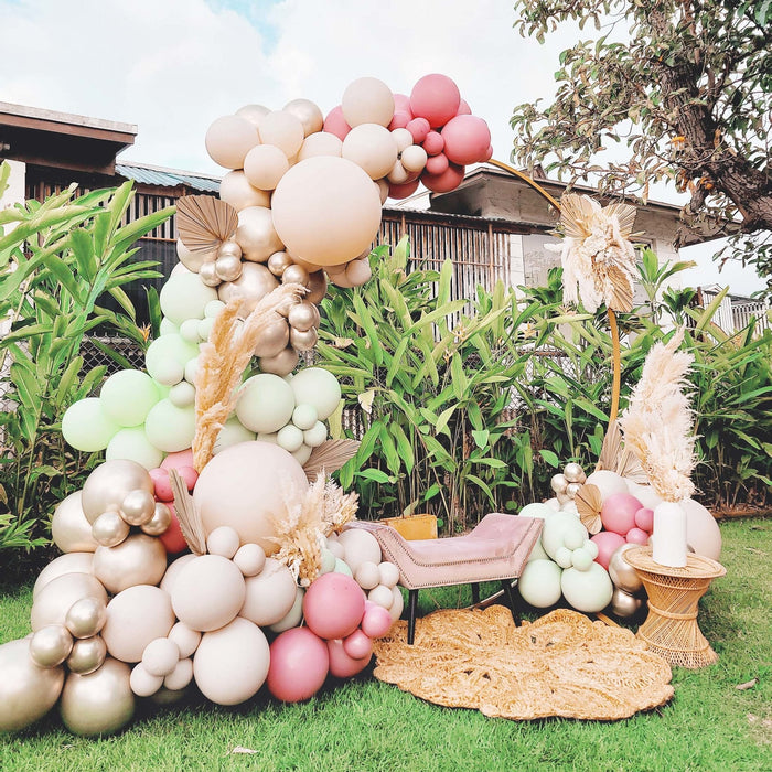Outdoor balloon arch cluster with pale pink, cream, and gold latex balloons