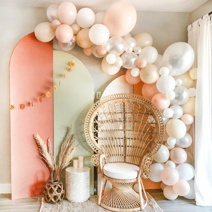 Balloon arch with cream, white, and blush pink round balloons and gold chair accent