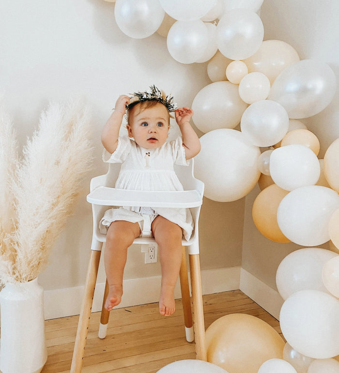 Round cream and white balloon cluster with a baby seated in front