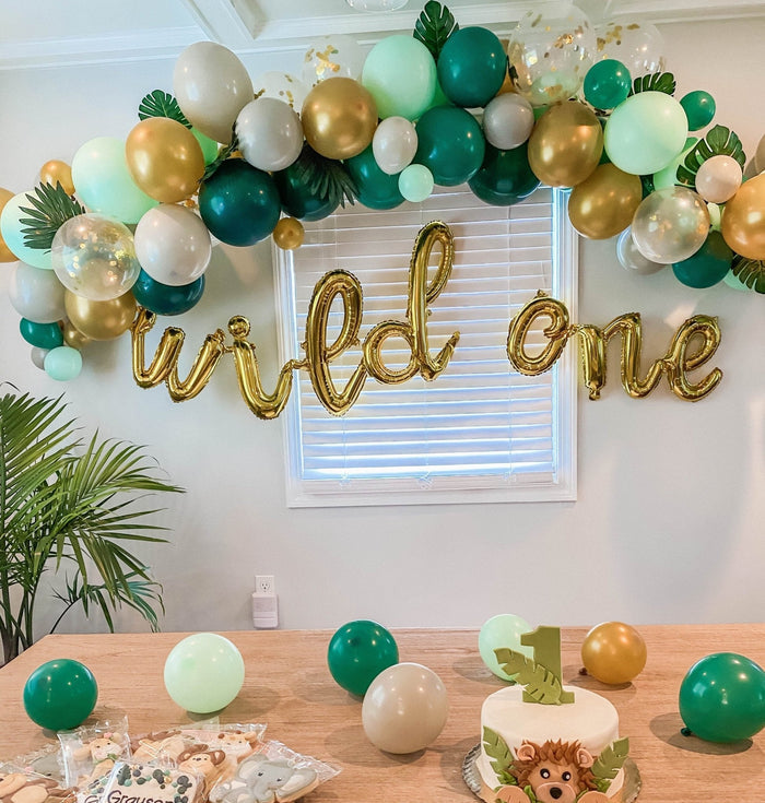 Balloon garland with green, teal, and gold latex balloons above a party table