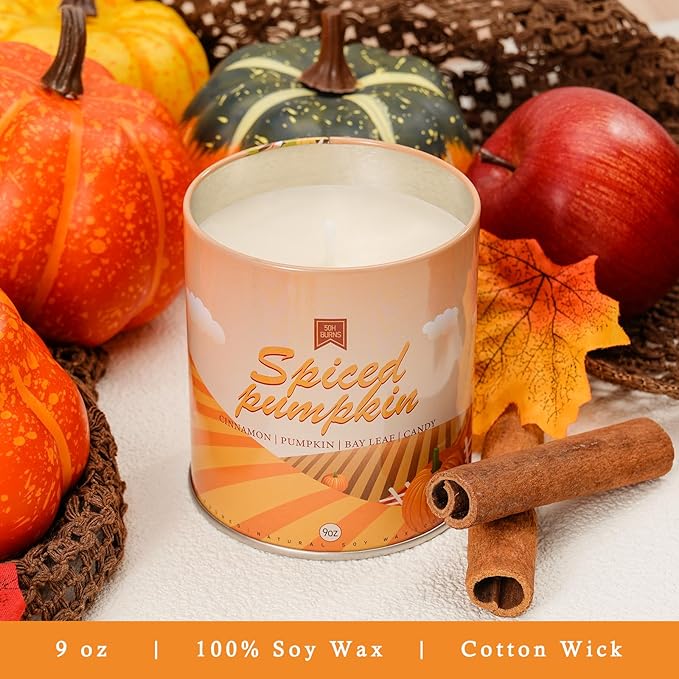 Spiced pumpkin scented candle in glass jar with cinnamon sticks and autumn pumpkins