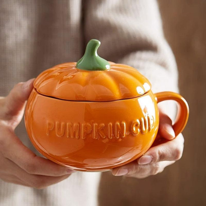 Pumpkin-shaped ceramic mug with domed lid, orange glaze, green stem, side handle