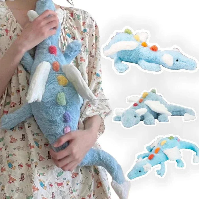 Light blue plush dragon held in arms, with white wings and colorful belly spots