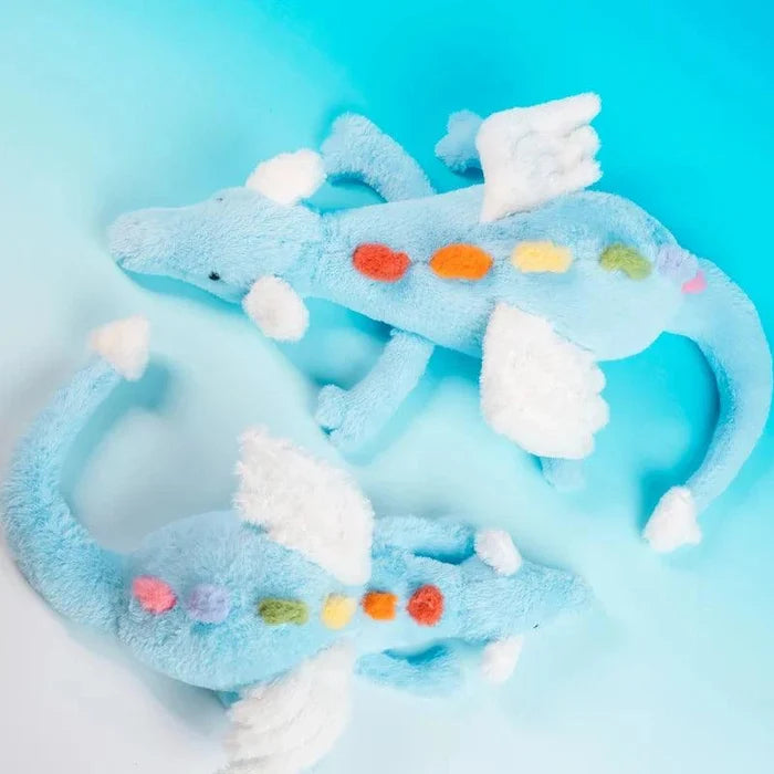 Light blue plush dragon with white wings and multicolor dot belly, stretched on side