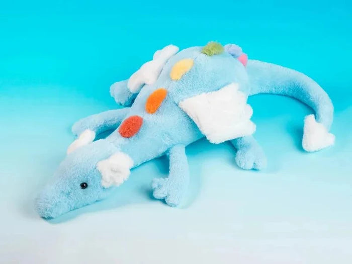Light blue plush dragon with white muzzle and colorful pom-pom back, lying down
