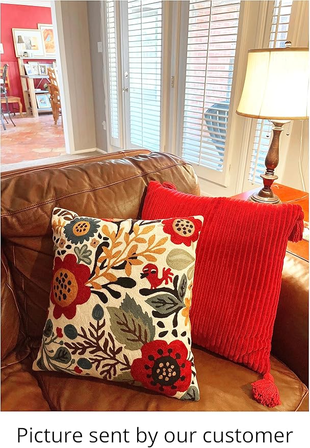 Floral bird throw pillow cover on a couch, paired with a ribbed red pillow.