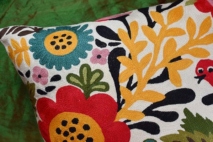 Close-up of floral bird cushion cover with teal and yellow flowers on light fabric.