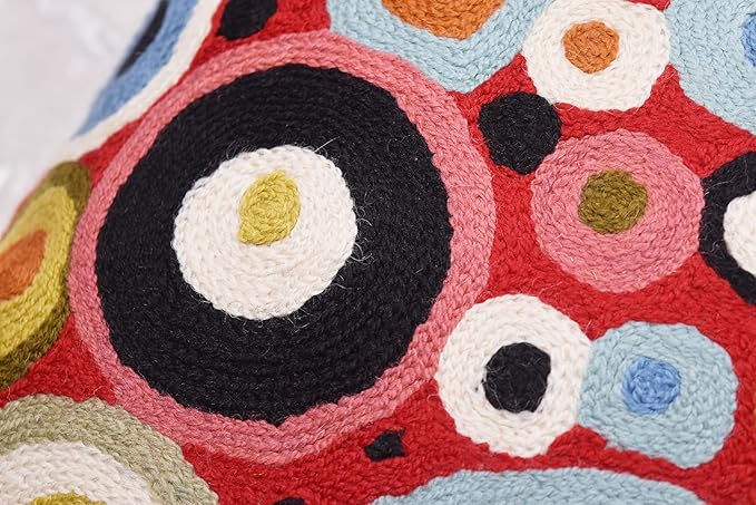Close-up of red pillow cover front with blue and black circular embroidered details