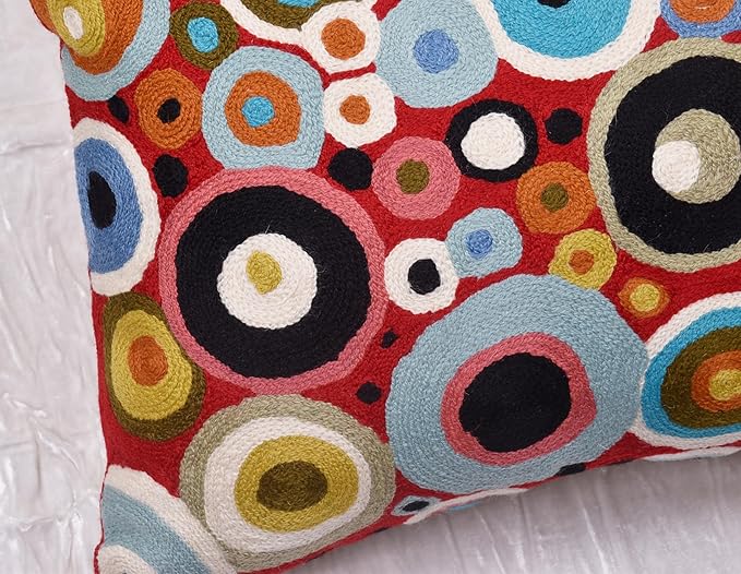 Red pillow cover front with layered rings in blue, black, and tan tones