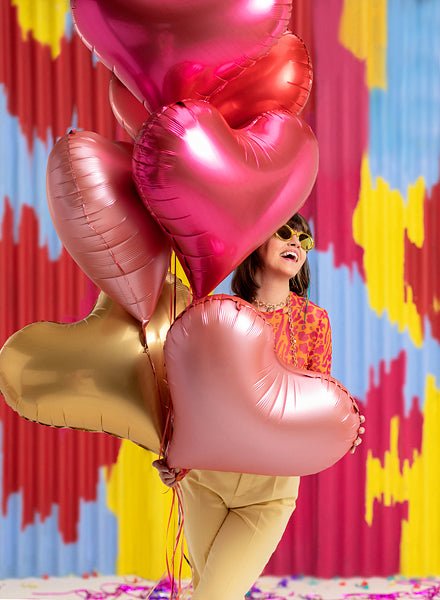 Cluster of heart-shaped foil balloons in pink, red, and gold