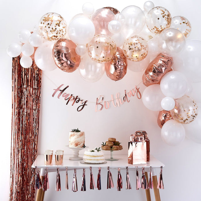 Rose gold and white balloon arch garland with metallic balloons and floral confetti