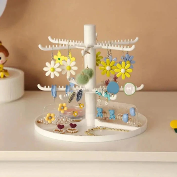 White tiered earring stand with daisy flowers and blue earrings on round base