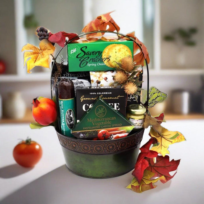 Green handled gift basket filled with packaged crackers, sweets, and jars, with autumn leaves