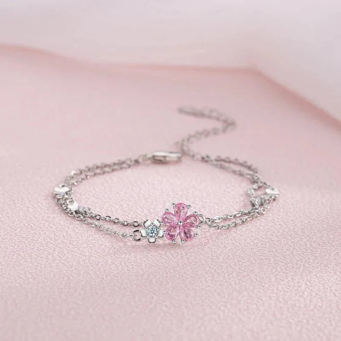 Silver charm bracelet with pink cherry blossom flower centerpiece and side charms