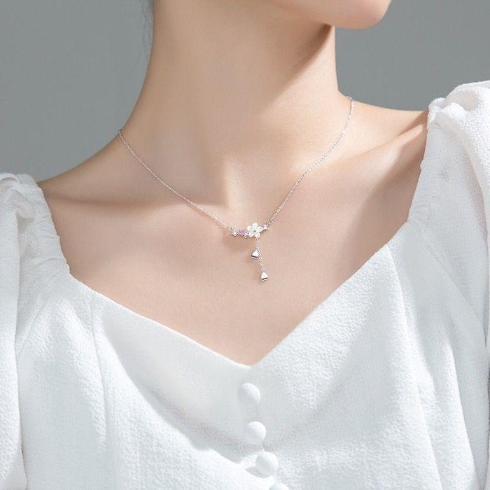 Silver tone necklace with small flower centerpiece and long dangling charm