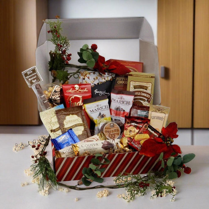Large Christmas candy gift box with assorted chocolates and cookies, open with greenery