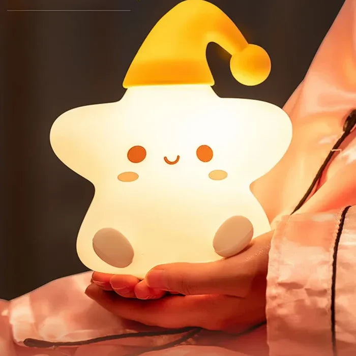 Silicone star LED night light held in hands, white body with yellow top and glow