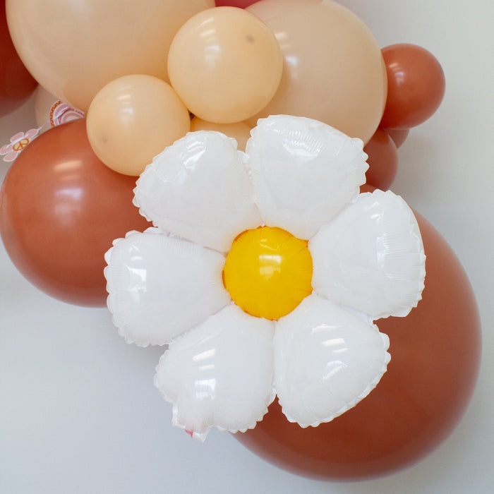 White daisy foil balloon with yellow center on top of orange balloons