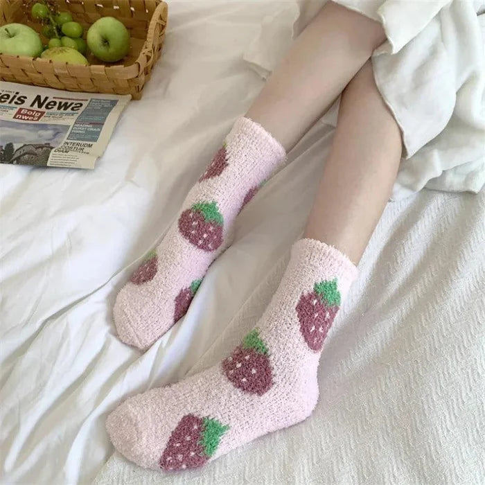 Soft plush sleeping socks in light pink with berry and green leaf pattern on feet