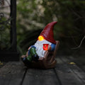 Solar-powered garden gnome figurine in a wooden sled holding a lantern, warm glow
