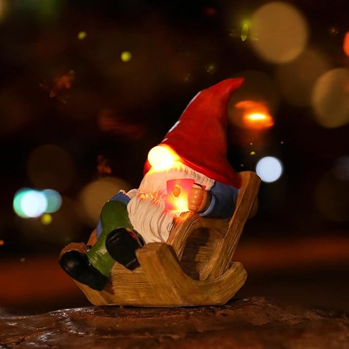 Close-up solar garden gnome figurine in wooden sled with red hat and glowing lantern light