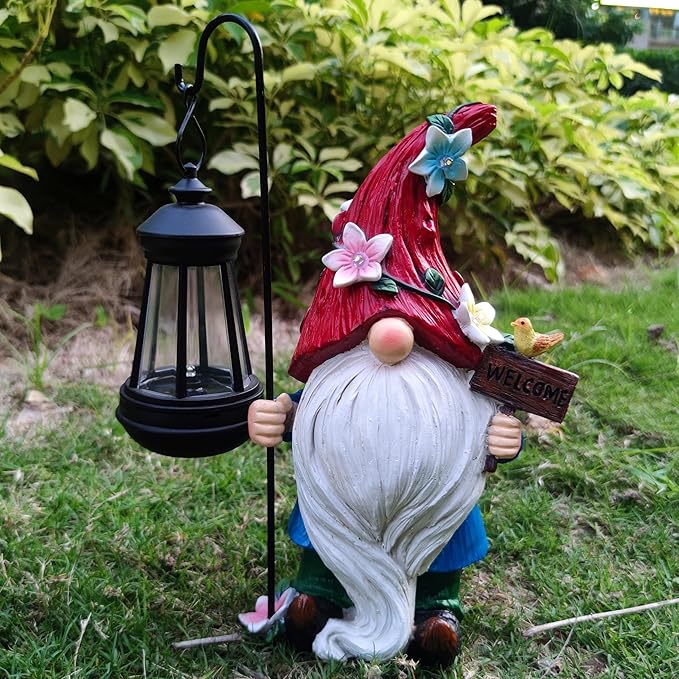 Solar garden gnome statue with a red flower hat and a black lantern with warm glowing lights