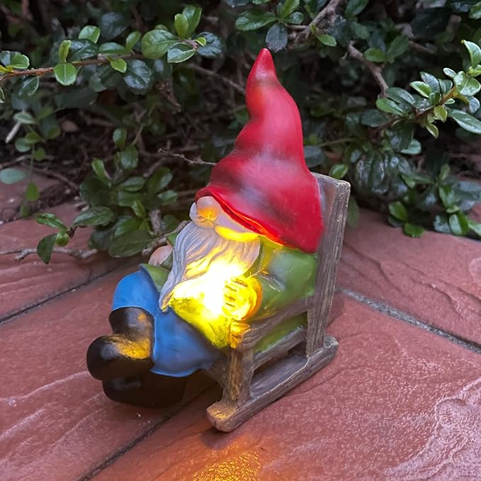 Solar gnome figurine on patio tiles, red hat, white beard, glowing lantern light