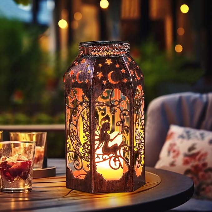 Bronze metal lantern with fairy and moon cutout design, glowing on patio table