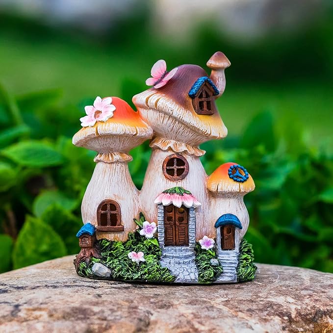 Fairy house garden statue on stone with glowing doors and windows, pink flowers and moss