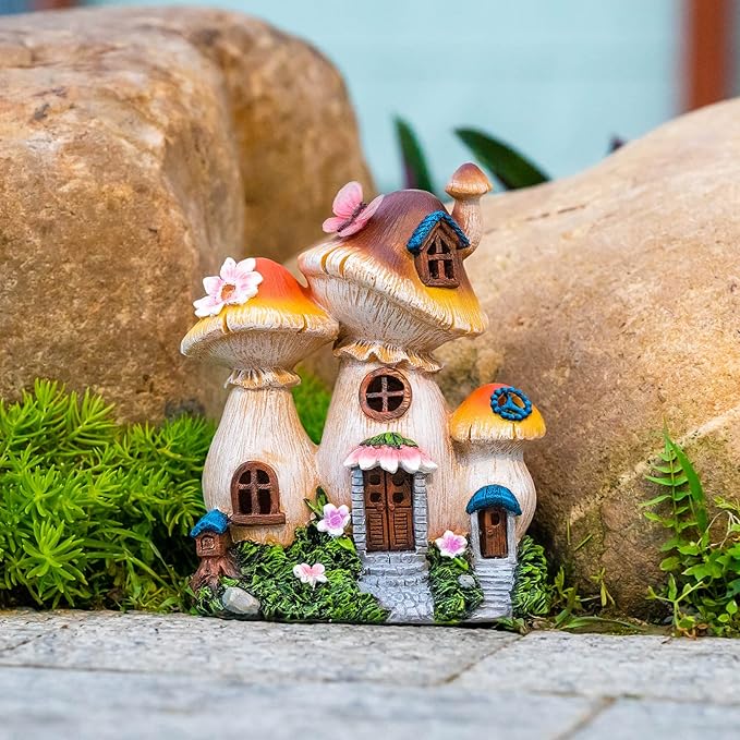 Lit mushroom fairy house garden statue nestled among rocks, moss, and small pink flowers