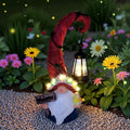 Solar gnome figurine holding a black lantern with warm LED lights, red hat and white beard