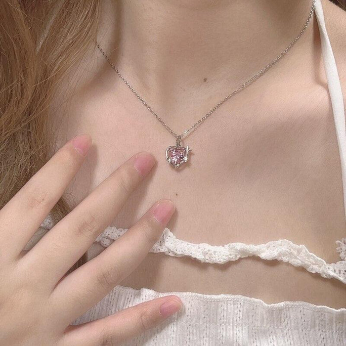 Heart crystal pendant necklace with small pink stone pendant on silver chain on model