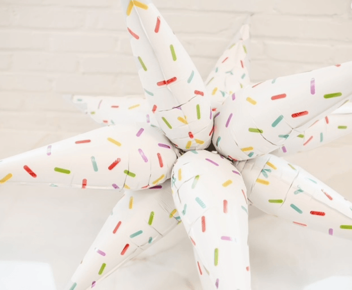 Starburst balloon cluster with white balloons and multicolor sprinkle stripe detail