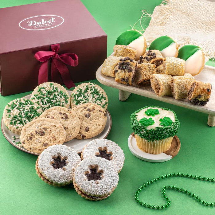Assorted frosted cookies and cupcakes, including green-decorated sugar cookies and tray treats