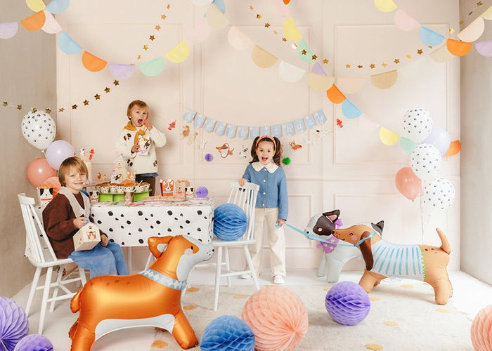 Bulldog-style character balloons standing on a party floor with children